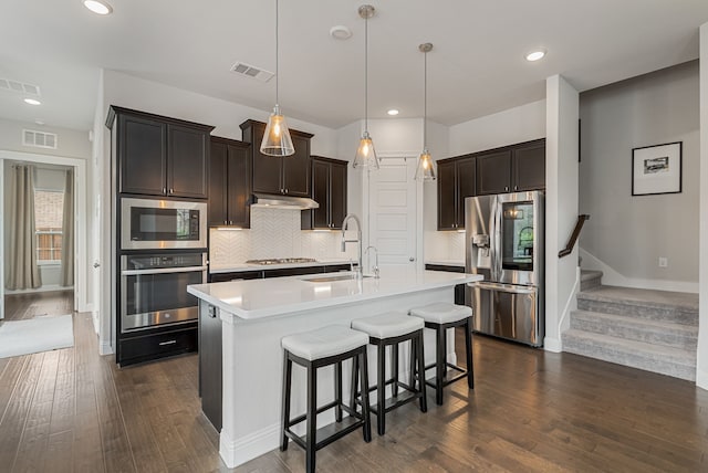 kitchen with a sink, stainless steel appliances, dark wood finished floors, and visible vents