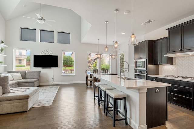 kitchen featuring stainless steel appliances, a sink, light countertops, open floor plan, and under cabinet range hood