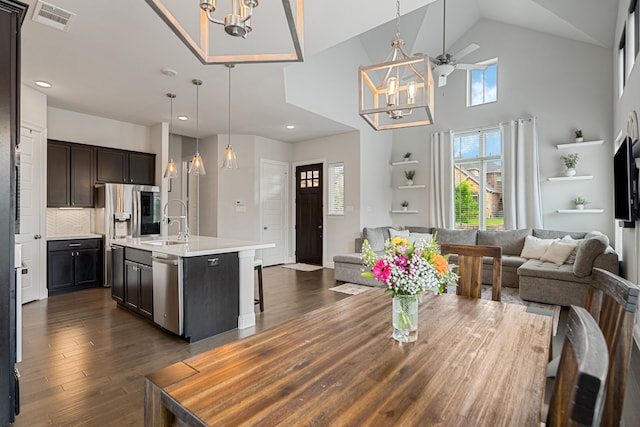 dining space with visible vents, dark wood-style floors, high vaulted ceiling, recessed lighting, and ceiling fan with notable chandelier