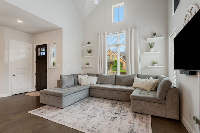 living room with baseboards, ceiling fan, dark wood-style floors, and high vaulted ceiling