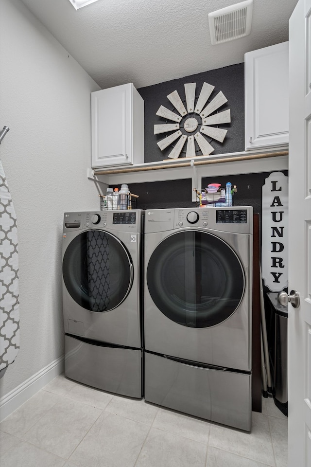 washroom featuring a textured ceiling, visible vents, cabinet space, baseboards, and washer and dryer