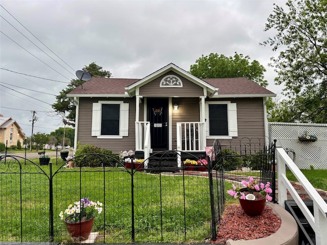 bungalow featuring a porch, a shingled roof, fence private yard, and a front lawn