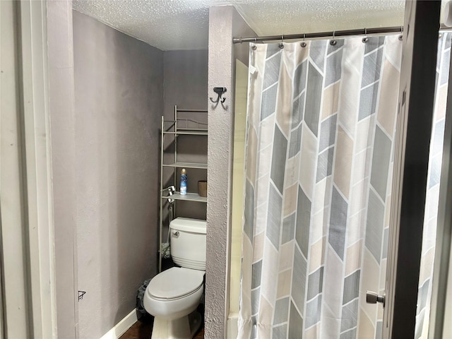 full bath featuring toilet, a textured ceiling, and a shower with curtain