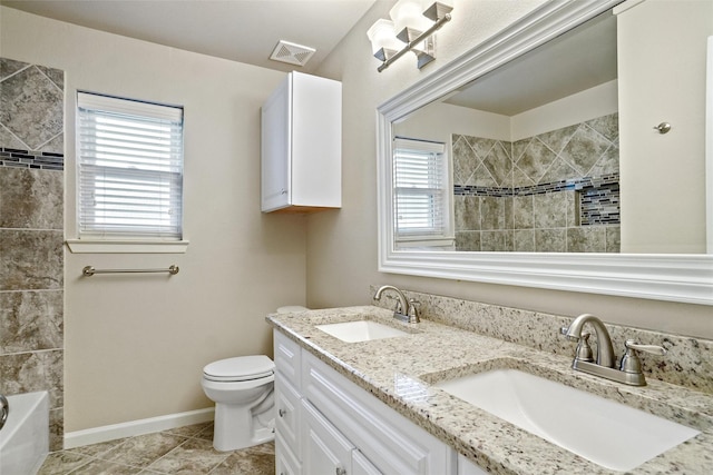 bathroom with toilet, visible vents, a tile shower, and a sink
