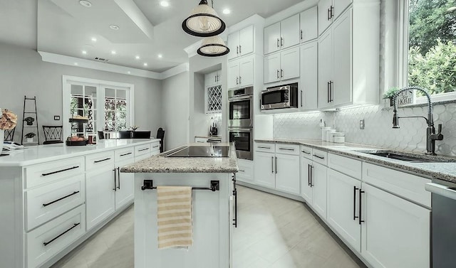 kitchen featuring decorative backsplash, a center island, appliances with stainless steel finishes, a sink, and white cabinetry