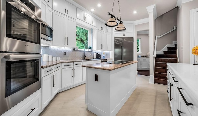 kitchen featuring a kitchen island, stainless steel appliances, decorative backsplash, and white cabinetry