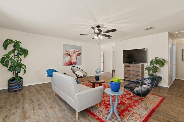 living area with baseboards, ceiling fan, wood finished floors, and visible vents