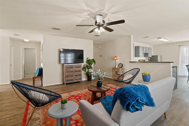 living room with a ceiling fan, baseboards, visible vents, and wood finished floors