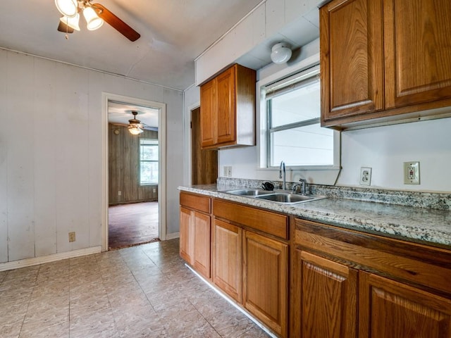 kitchen featuring a sink, a ceiling fan, brown cabinets, and light countertops