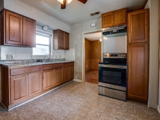 kitchen with visible vents, under cabinet range hood, stainless steel electric stove, brown cabinets, and a sink