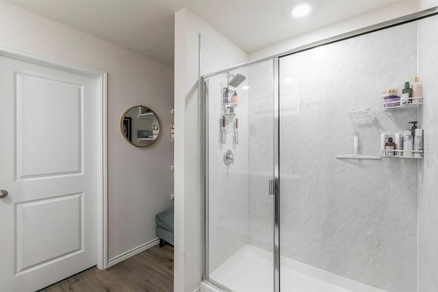 bathroom featuring baseboards, a stall shower, and wood finished floors