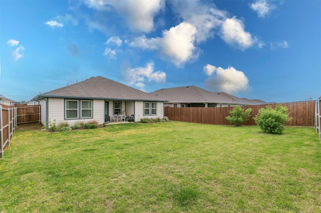 rear view of property featuring a fenced backyard, a patio, a lawn, and roof with shingles