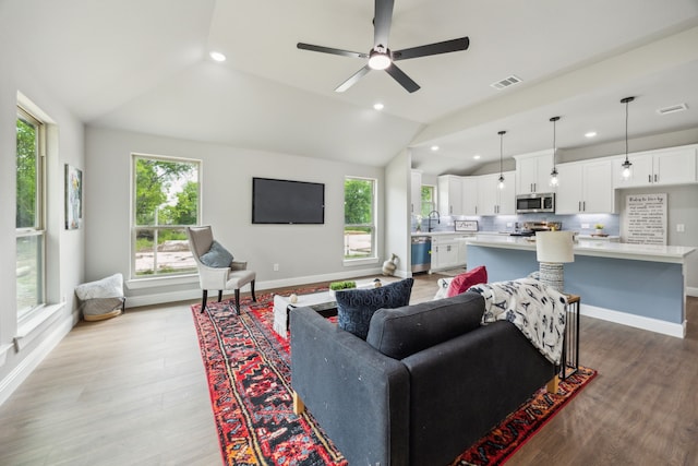 living room with baseboards, visible vents, wood finished floors, and vaulted ceiling