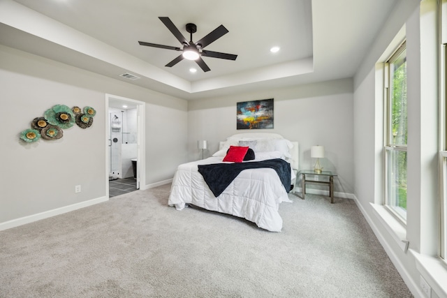 carpeted bedroom featuring visible vents, baseboards, recessed lighting, connected bathroom, and a tray ceiling