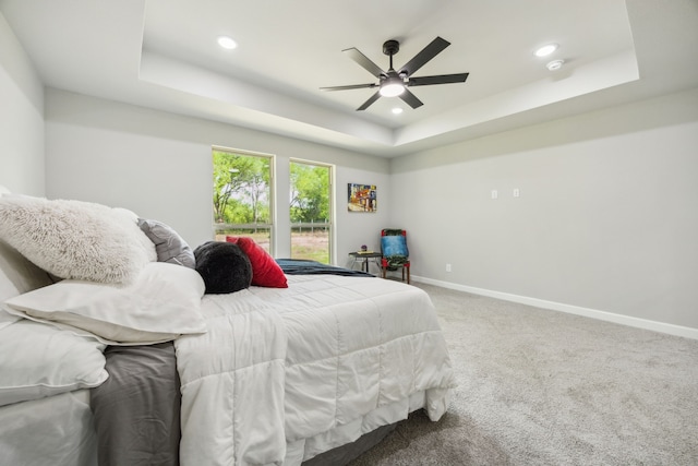 carpeted bedroom with baseboards, a ceiling fan, a tray ceiling, and recessed lighting