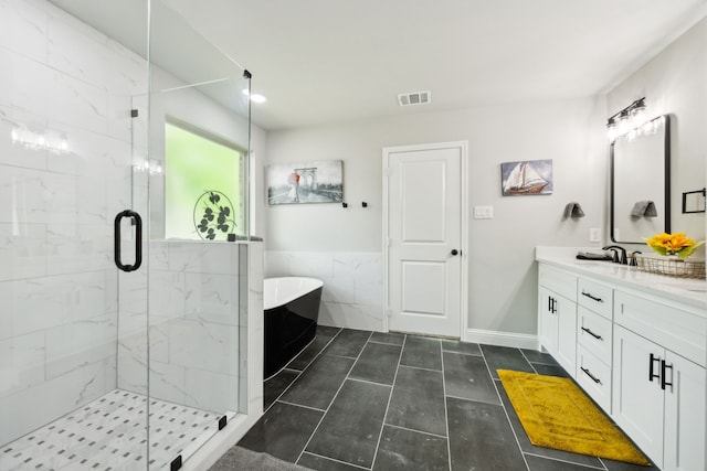 full bathroom featuring vanity, a freestanding tub, a shower stall, and visible vents
