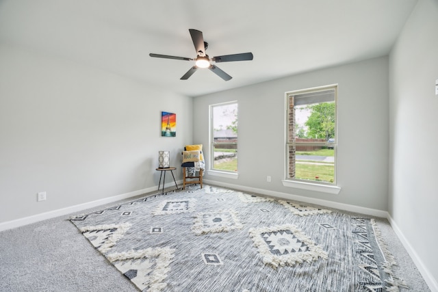 carpeted spare room featuring baseboards and ceiling fan