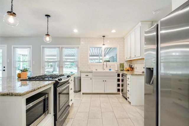 kitchen with a sink, appliances with stainless steel finishes, backsplash, and a wealth of natural light