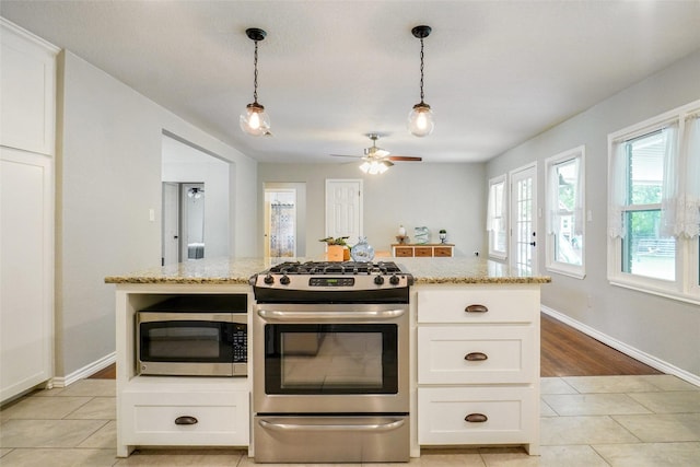 kitchen with light tile patterned floors, white cabinets, light stone countertops, and stainless steel appliances