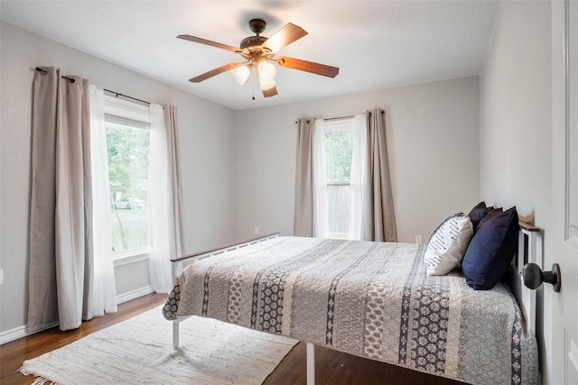 bedroom with baseboards, multiple windows, a ceiling fan, and wood finished floors