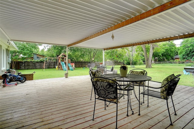 wooden terrace with a playground, outdoor dining space, a yard, and a fenced backyard