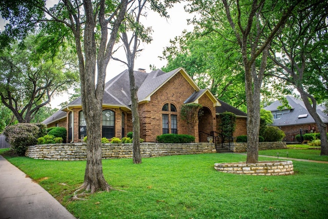 view of front of house with brick siding, a front lawn, roof with shingles, and a chimney