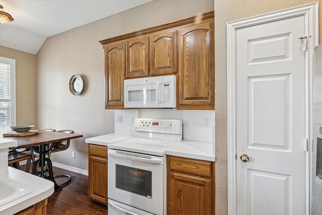 kitchen featuring dark wood-style flooring, white appliances, light countertops, brown cabinetry, and baseboards