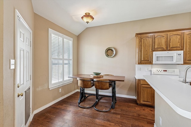 kitchen featuring baseboards, white microwave, dark wood-style floors, and brown cabinets