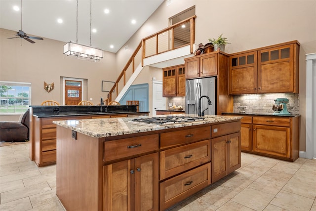 1009 Western Dr, Woodway, TX 76712 - kitchen featuring a kitchen island with sink, a ceiling fan, appliances with stainless steel finishes, tasteful backsplash, and high vaulted ceiling