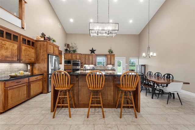 1009 Western Dr, Woodway, TX 76712 - kitchen featuring high vaulted ceiling, a chandelier, brown cabinetry, stainless steel appliances, and decorative backsplash