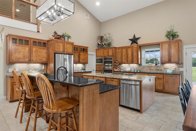 1009 Western Dr, Woodway, TX 76712 - kitchen featuring high vaulted ceiling, a center island with sink, brown cabinets, and appliances with stainless steel finishes