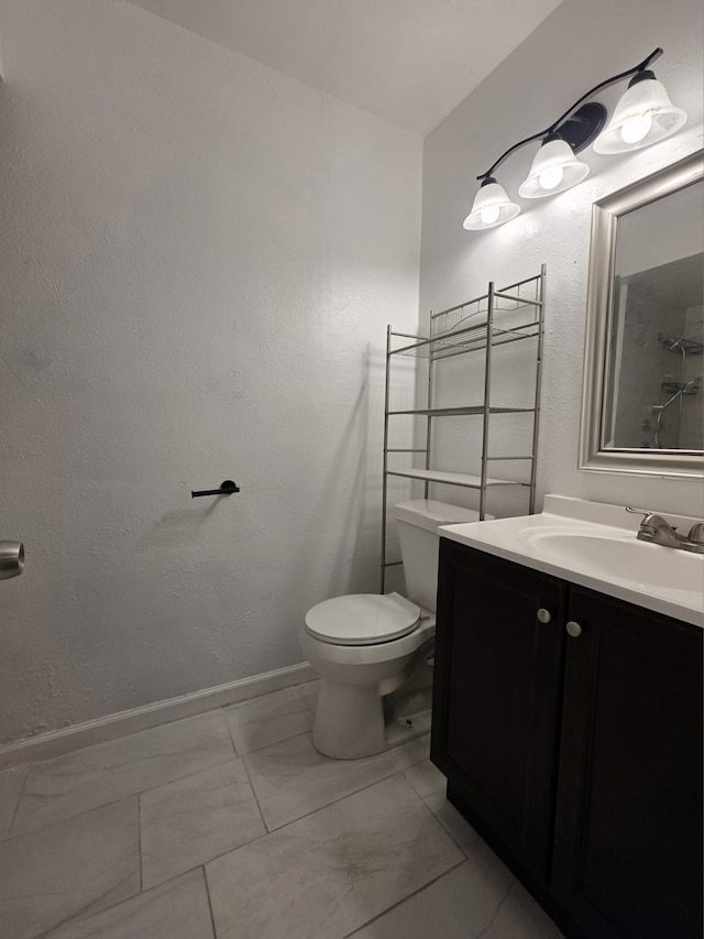 bathroom featuring toilet, baseboards, marble finish floor, and vanity