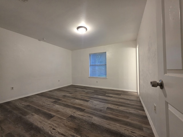 unfurnished room featuring baseboards and dark wood-style floors