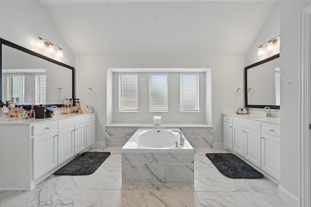 full bath featuring a sink, marble finish floor, two vanities, lofted ceiling, and a garden tub