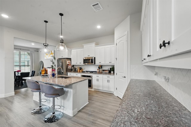 kitchen featuring visible vents, a sink, light wood finished floors, and stainless steel appliances
