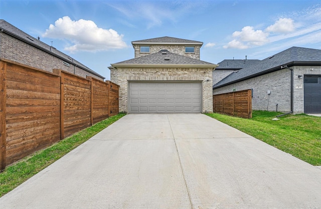 exterior space with a garage, a front lawn, fence, a shingled roof, and concrete driveway