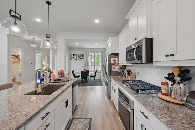 kitchen featuring light wood-style floors, a sink, plenty of natural light, and appliances with stainless steel finishes