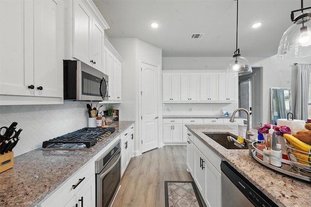 kitchen featuring visible vents, appliances with stainless steel finishes, a sink, light wood finished floors, and white cabinetry