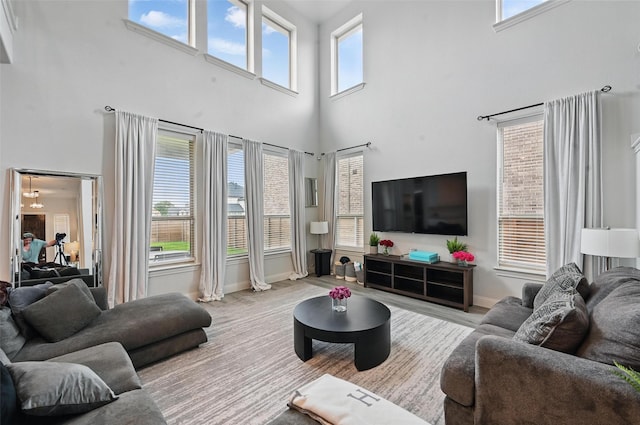 living room with a high ceiling, baseboards, and wood finished floors