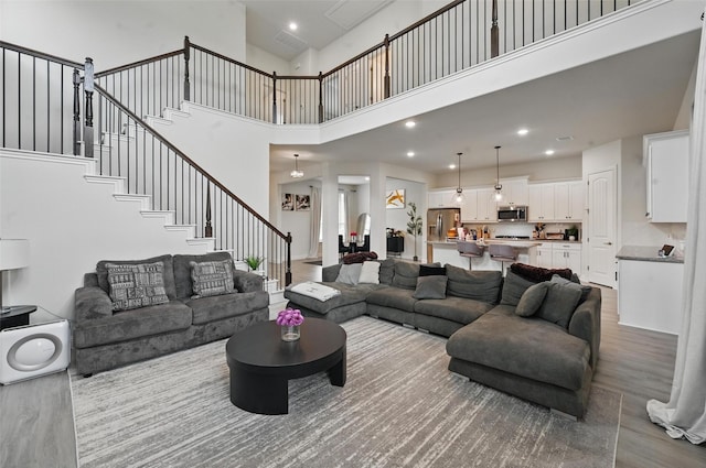 living area with visible vents, wood finished floors, stairway, a high ceiling, and recessed lighting