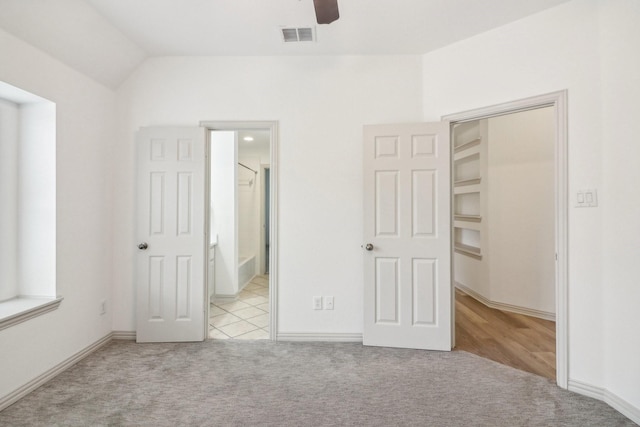 unfurnished bedroom featuring visible vents, carpet flooring, ensuite bath, and lofted ceiling
