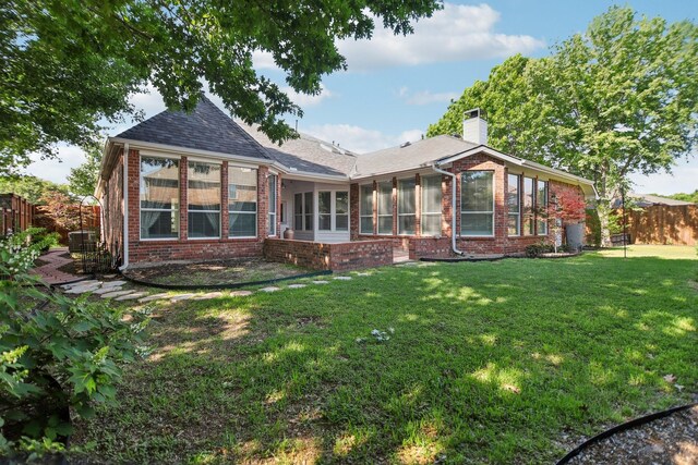 rear view of property featuring fence, a lawn, central AC, and brick siding