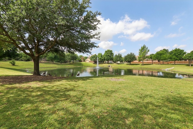 surrounding community featuring fence, a water view, and a lawn