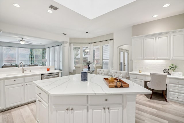 kitchen with backsplash, light wood-type flooring, a sink, and a center island