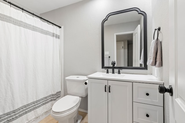 full bathroom with vanity, a textured wall, toilet, and curtained shower
