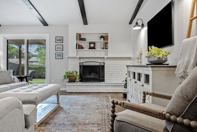 living area with wood finished floors, baseboards, beam ceiling, and a fireplace