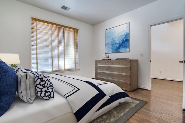 bedroom with visible vents, baseboards, and wood finished floors