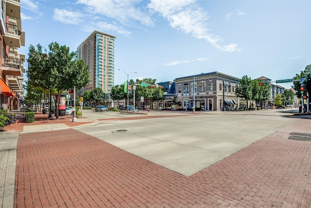 view of street featuring traffic lights, curbs, street lights, and sidewalks