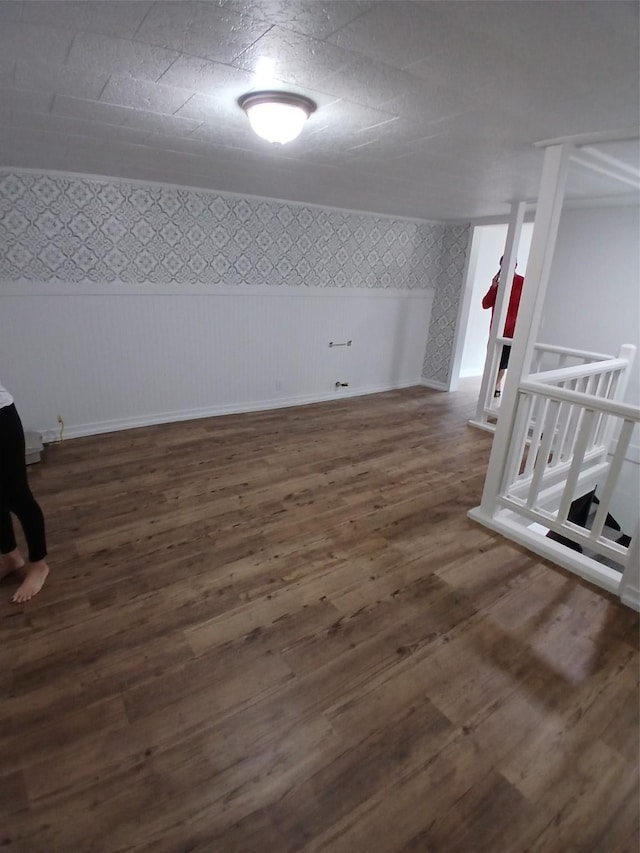 finished below grade area with baseboards, wallpapered walls, and wood finished floors