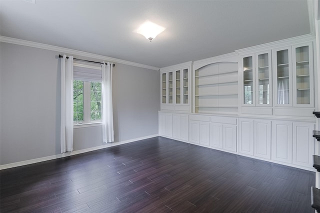 empty room featuring crown molding, dark wood-style flooring, and baseboards